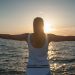 A woman stands with open arms, embracing the sunset over the ocean. San Juan Bautista, Spain.